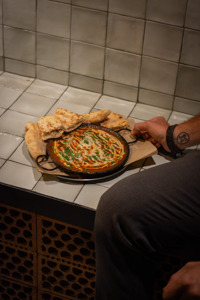 Shakshuka, huevos con salsa de tomate, pimientos, cebolla i tahini en restaurante Dos Manos Pita Bar del barri de Gràcia de Barcelona
