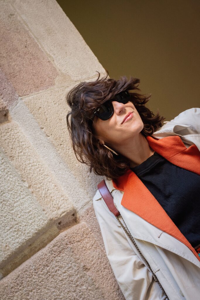 Look con gabardina y blazer de lana naranja vintage, pantalones negros arrugados, pañuelo de seda en la cintura y bailarinas Repetto Paris