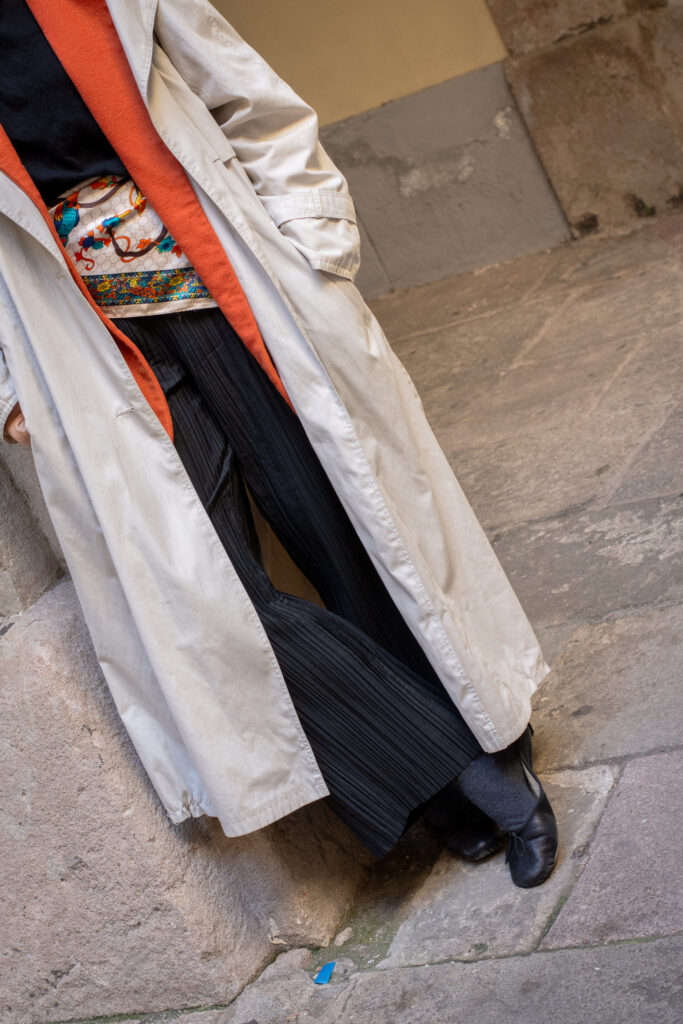 Look con gabardina y blazer de lana naranja vintage, pantalones negros arrugados, pañuelo de seda en la cintura y bailarinas Repetto Paris
