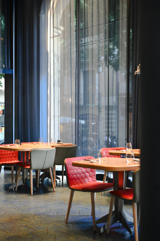 Interior Tunateca de Balfegó en la Diagonal de Barcelona con sillas rojas, cortinas azules y mesas de madera